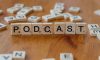 A wooden table topped with scrabble tiles that spell out the word podcast