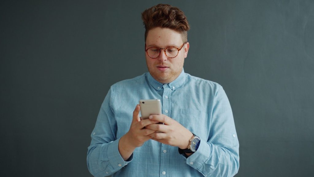Man in glasses looking at his phone.
