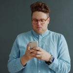 Man in glasses looking at his phone.