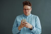 Man in glasses looking at his phone.