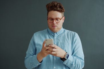Man in glasses looking at his phone.