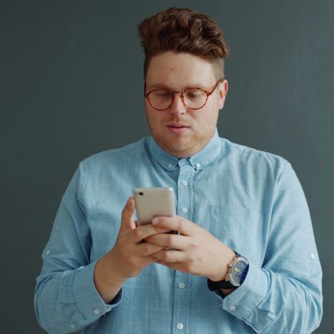 Man in glasses looking at his phone.