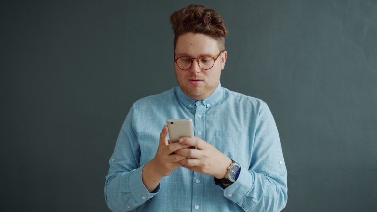 Man in glasses looking at his phone.