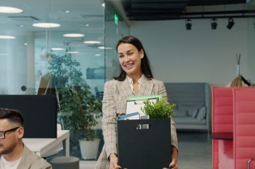 Woman carrying box of belongings leaving office
