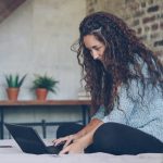 Woman with curly hair typing on a laptop