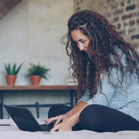 Woman with curly hair typing on a laptop