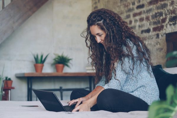 Woman with curly hair typing on a laptop