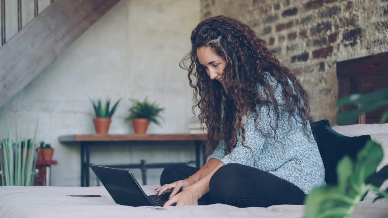 Woman with curly hair typing on a laptop