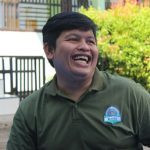 a man laughing while wearing a green shirt