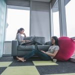 two women sitting on sofa and floor inside gray painted room