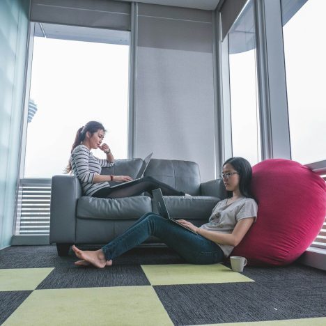 two women sitting on sofa and floor inside gray painted room