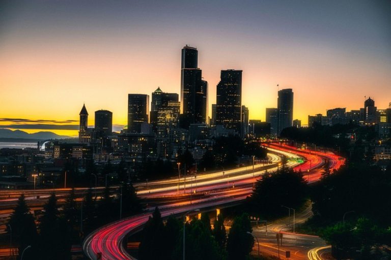 Skyline at sunset with highway light trails, symbolizing real-world driving risks and the need for legitimate car warranty companies and vehicle protection administrators like MotoAssure Admin.