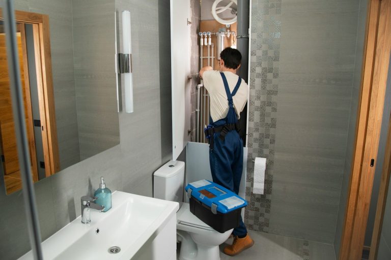 A plumber repairs plumbing in a bathroom.