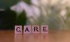 A wooden block spelling care on a table