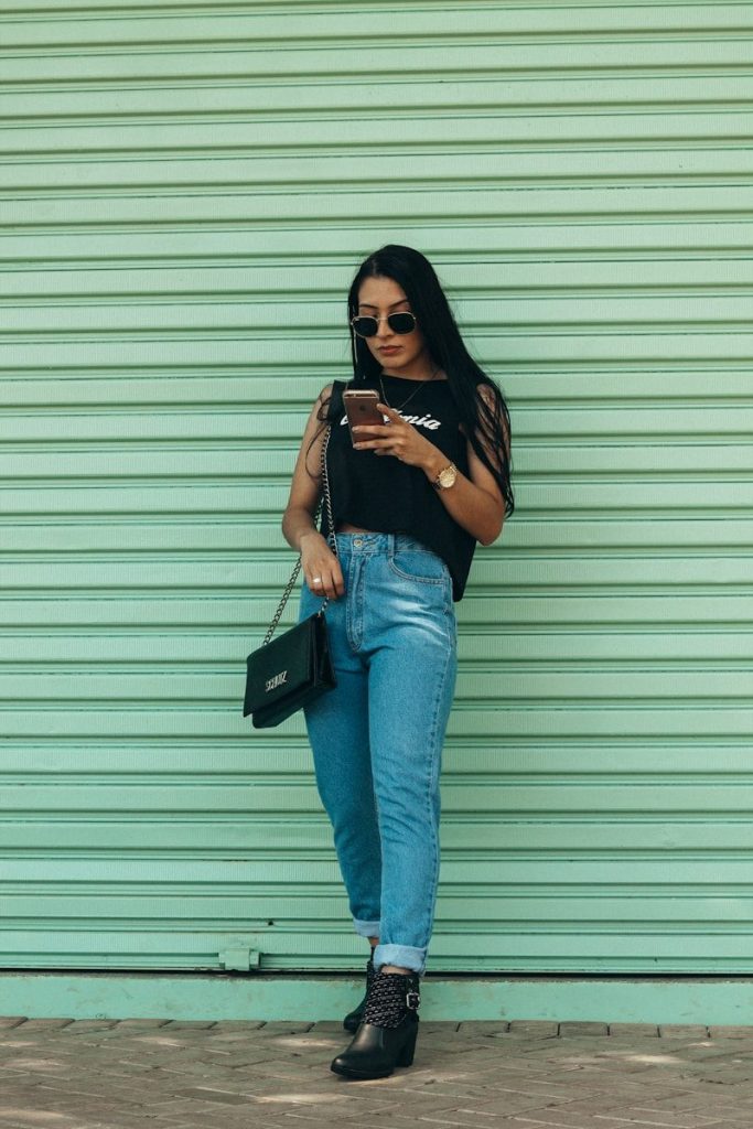 woman in black sleeveless top holding smartphone outdoors