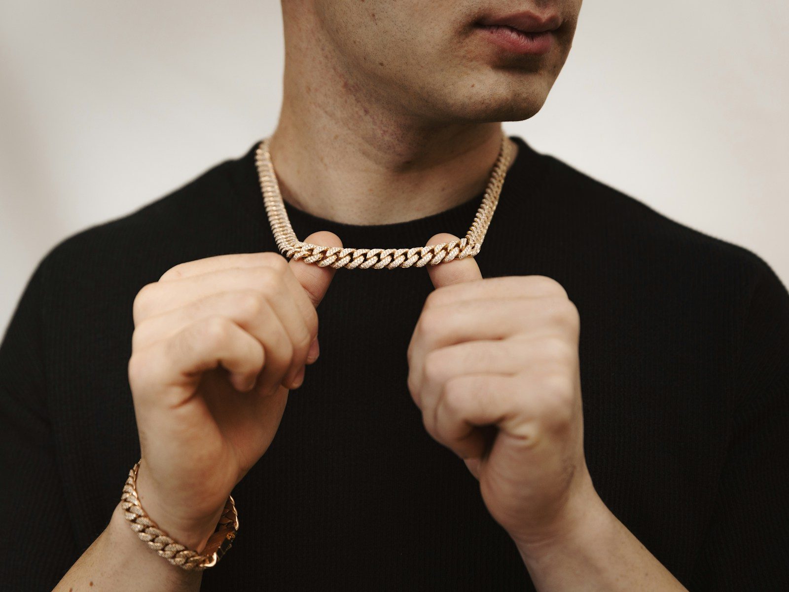 Man holding a rose gold chain necklace and bracelet