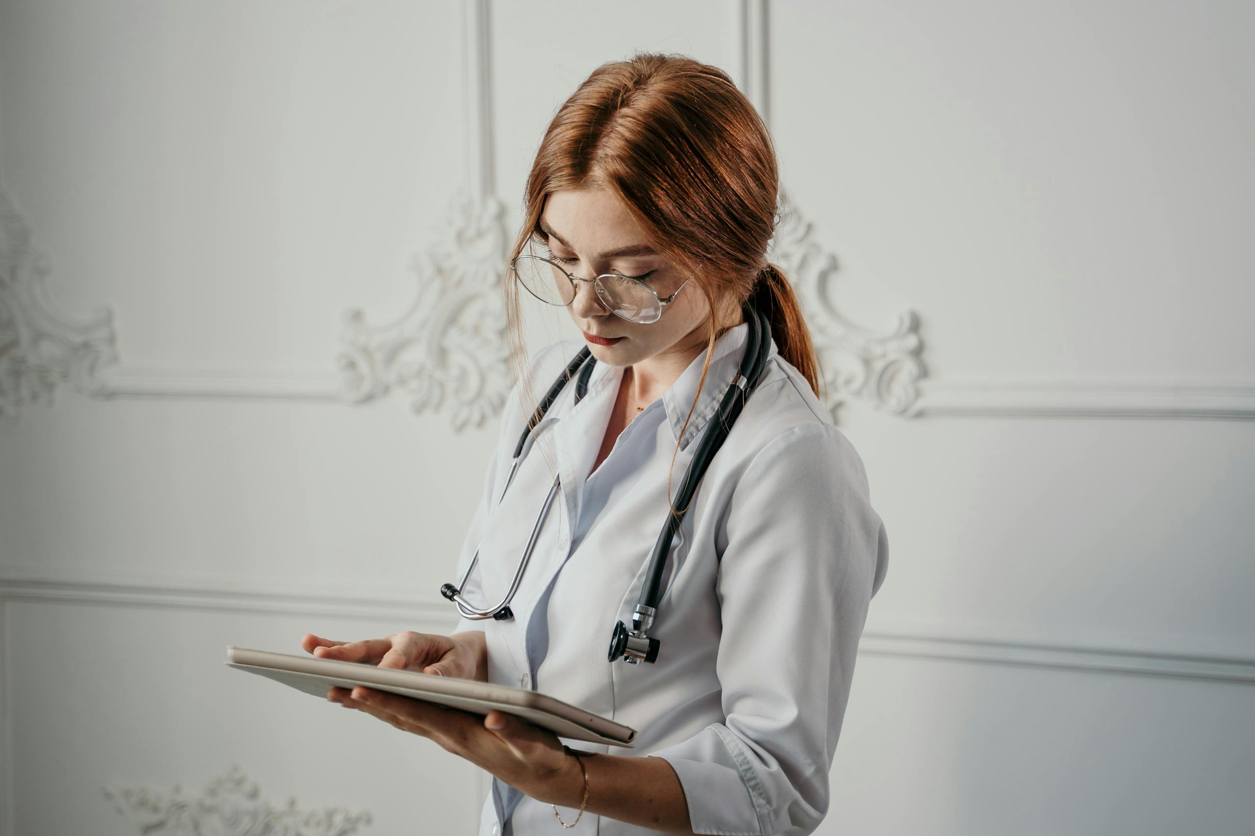 Female doctor in white coat using a tablet, emphasizing modern healthcare and technology.