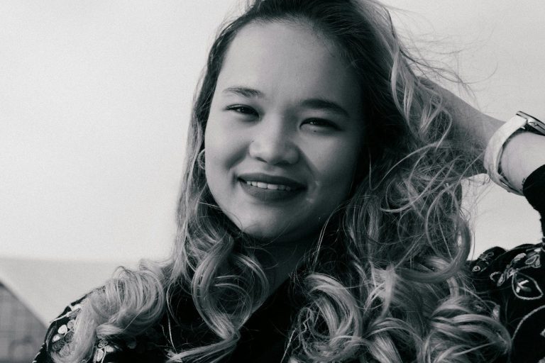 A young woman with curly hair smiles