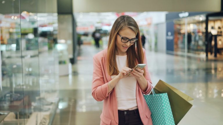 Woman using phone while shopping with bags