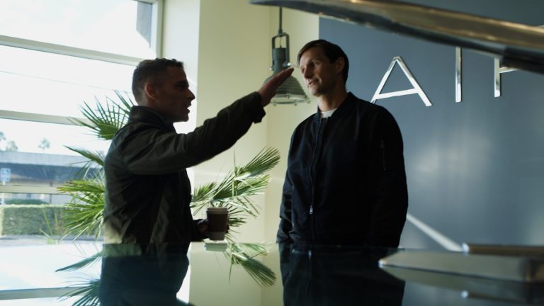 Two men talking near an airplane model.