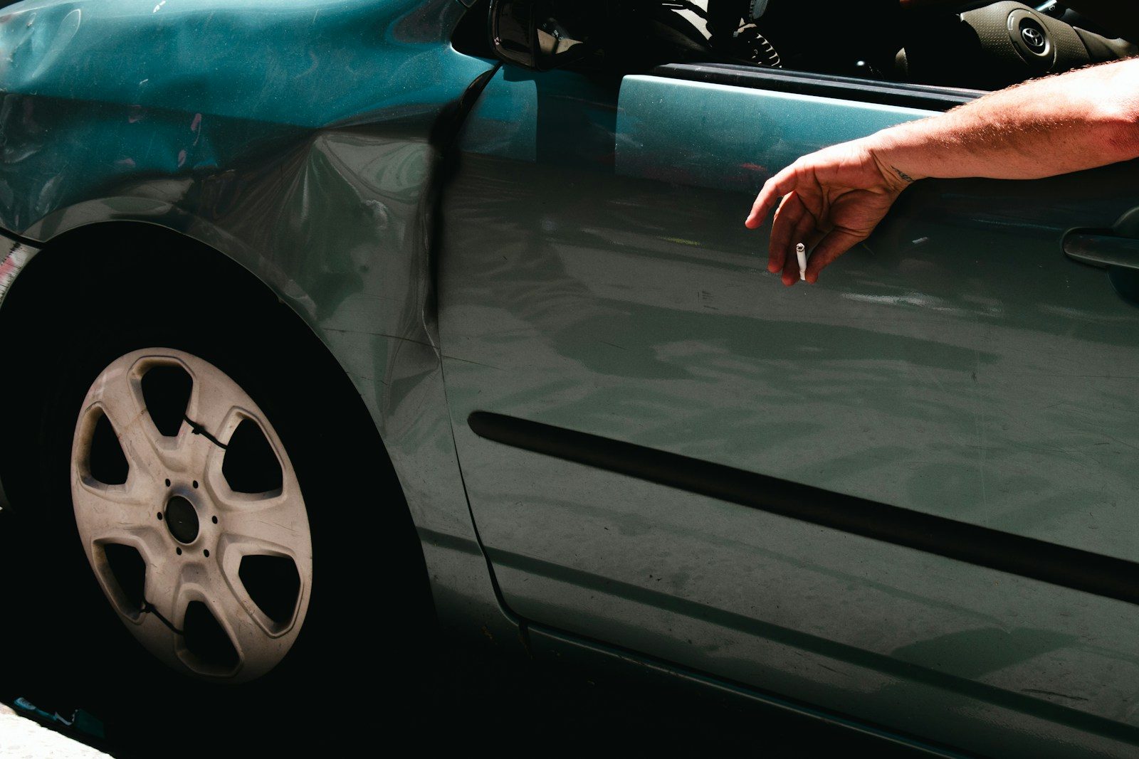 A man leaning out of a car with his hand on the hood
