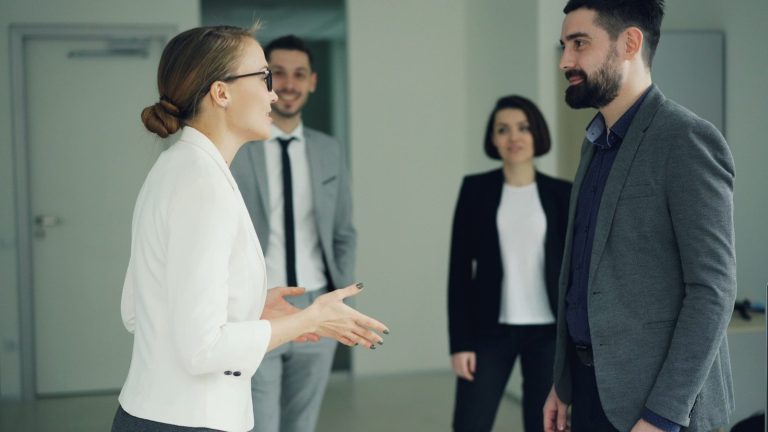 Two business people conversing, others observing.